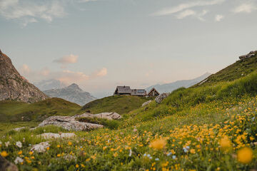 © Le refuge du Fond des Fours vue de loin avec les fleurs en été - Yann Allegre